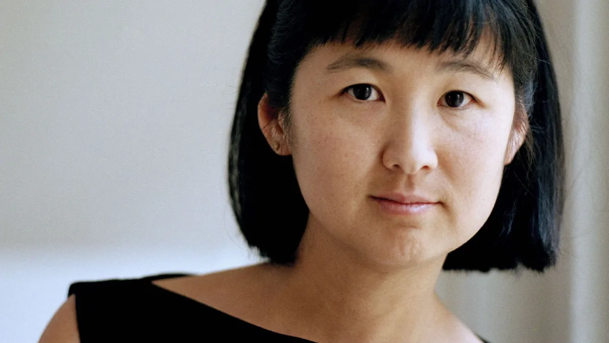 Maya Lin faces the camera wearing a black boatneck top in front of a white backdrop. Her hair is cut in a bob.
