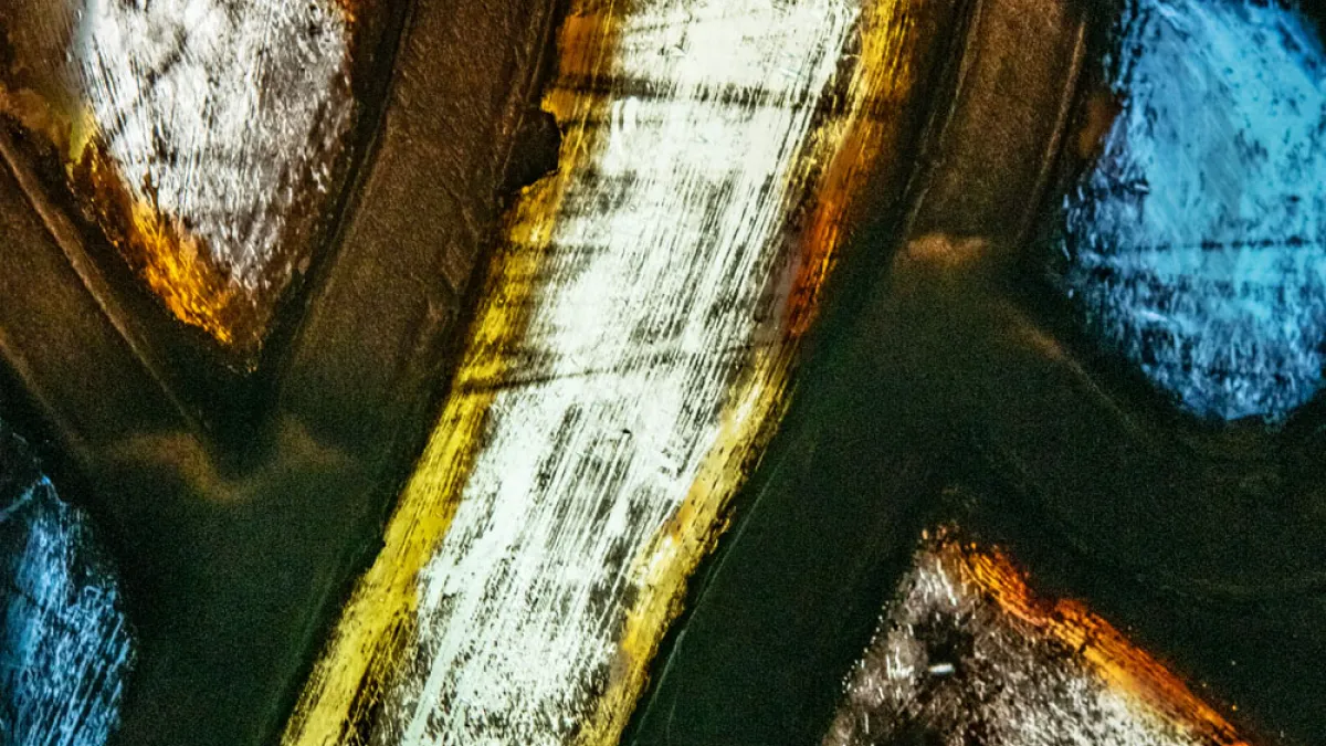 Extreme close up of stained glass with whites, yellows, oranges, and blues