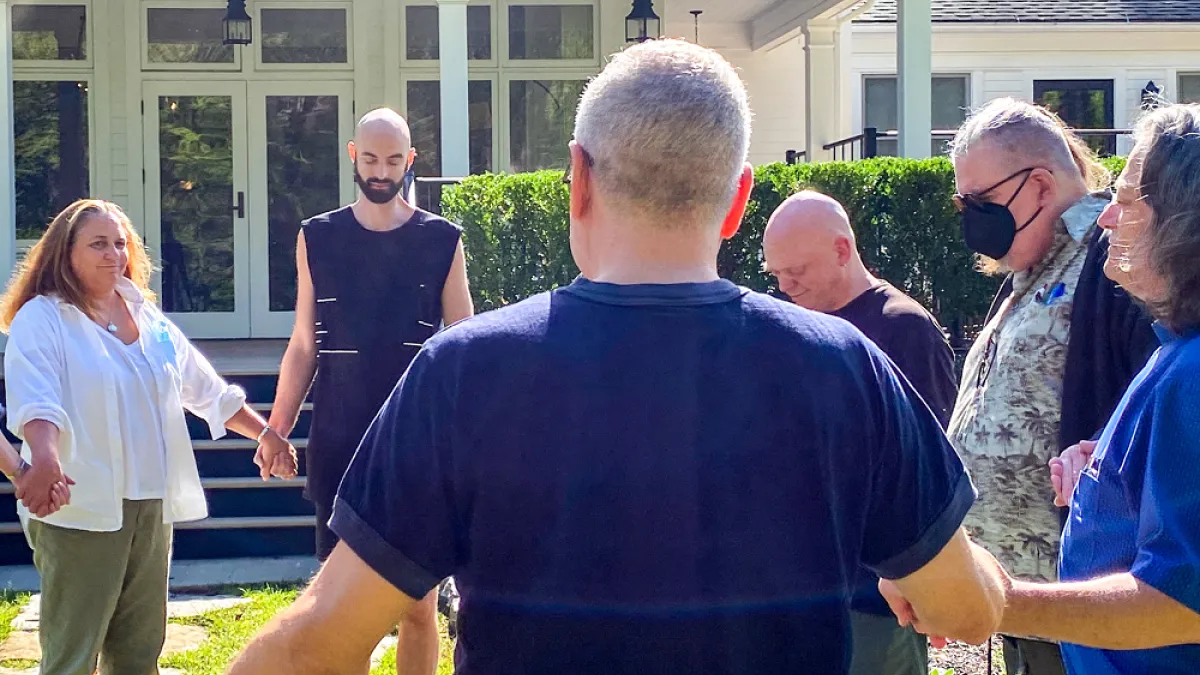 Retreatants hold hands in prayer and sunshine