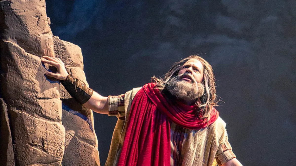A production still of Moses kneeling on a mountaintop