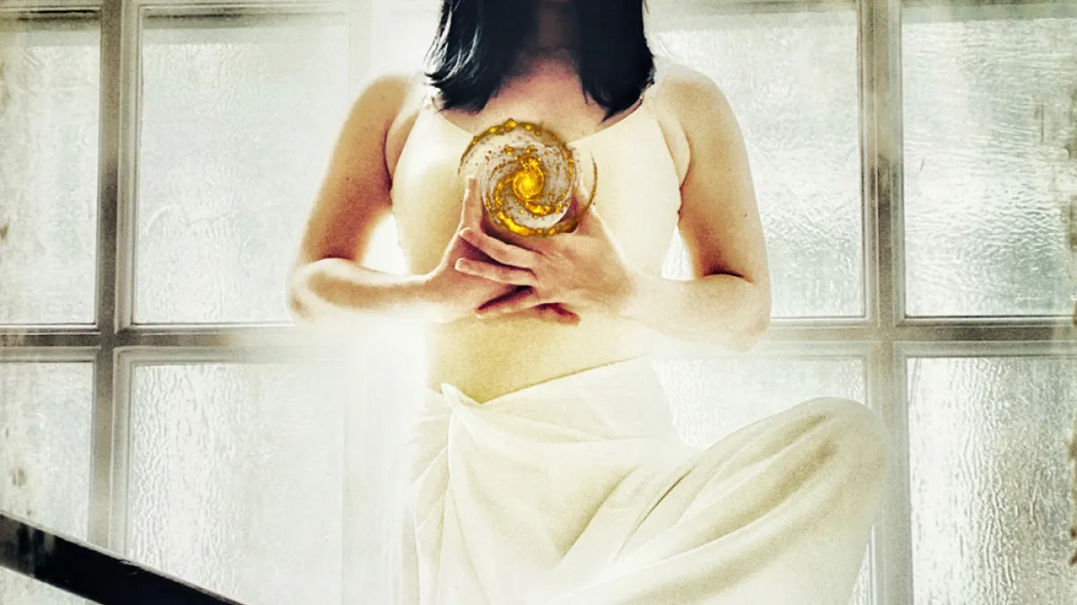 A dancer stands in front of a light-filled window in St. Paul's Chapel with a small universe floating in their hands