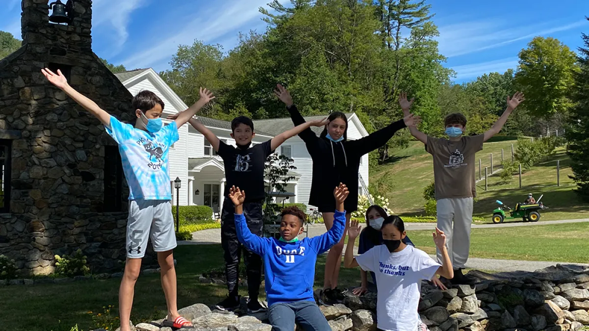 A group of kids posing on a stone wall at the Trinity Retreat Center