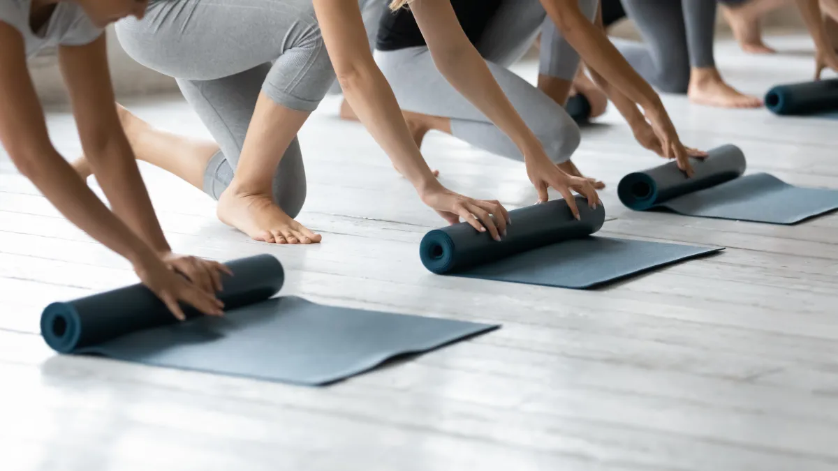 People are folding yoga mats in a line