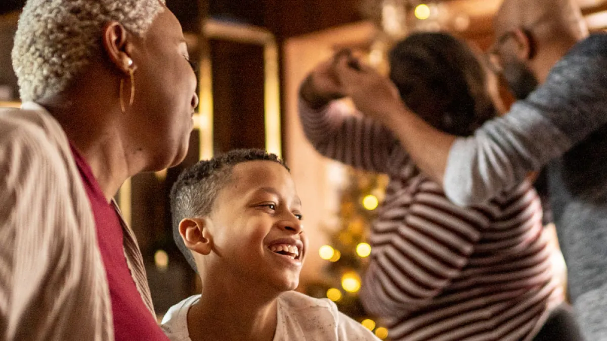 Families dancing in a living room with a Christmas tree