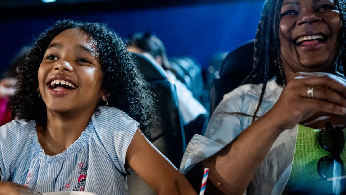 Mother and daughter duo laugh at the movie theater.