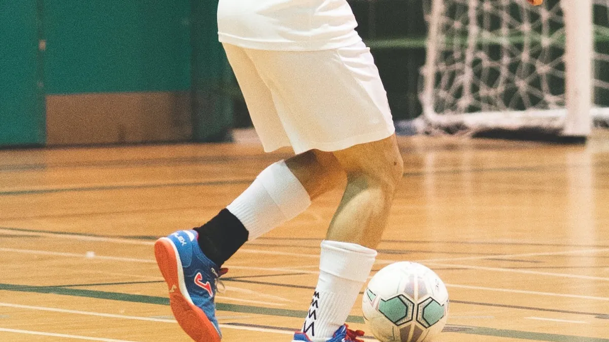 Man kicks soccer ball in gym