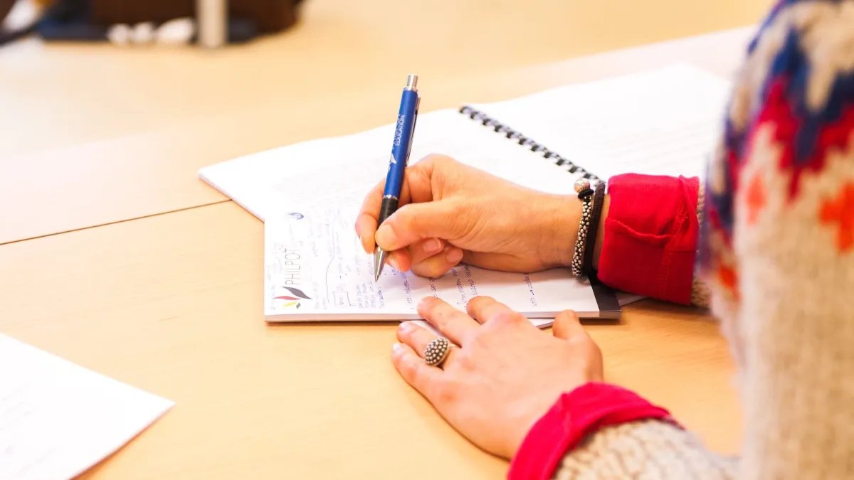 Woman takes notes in classroom