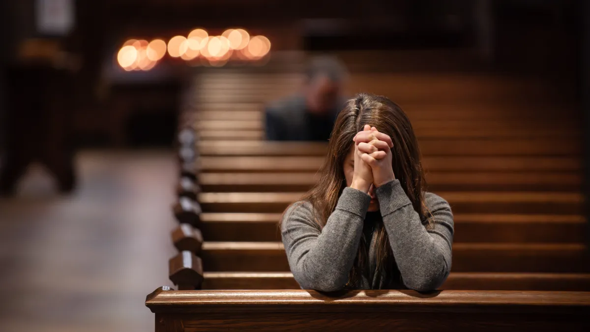 A person prays in a pew in Trinity Church