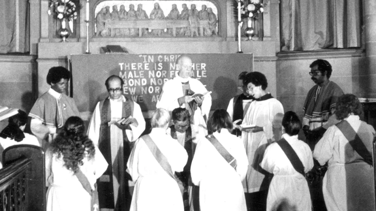 Women kneel at an altar during an ordination service