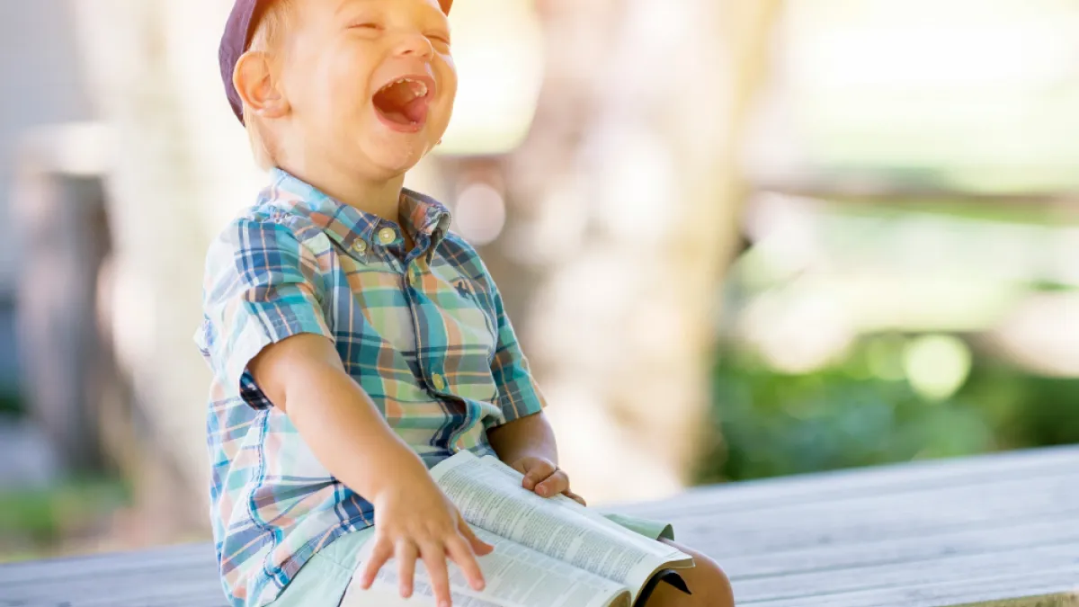 A laughing kid with a book