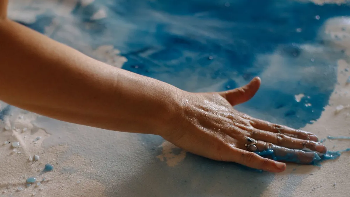 A hand is spreading the paint on the paper. 