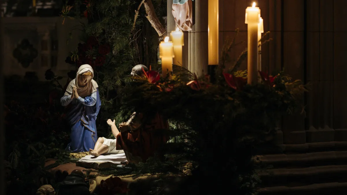 The figurine of Jesus's birth next to candles. 