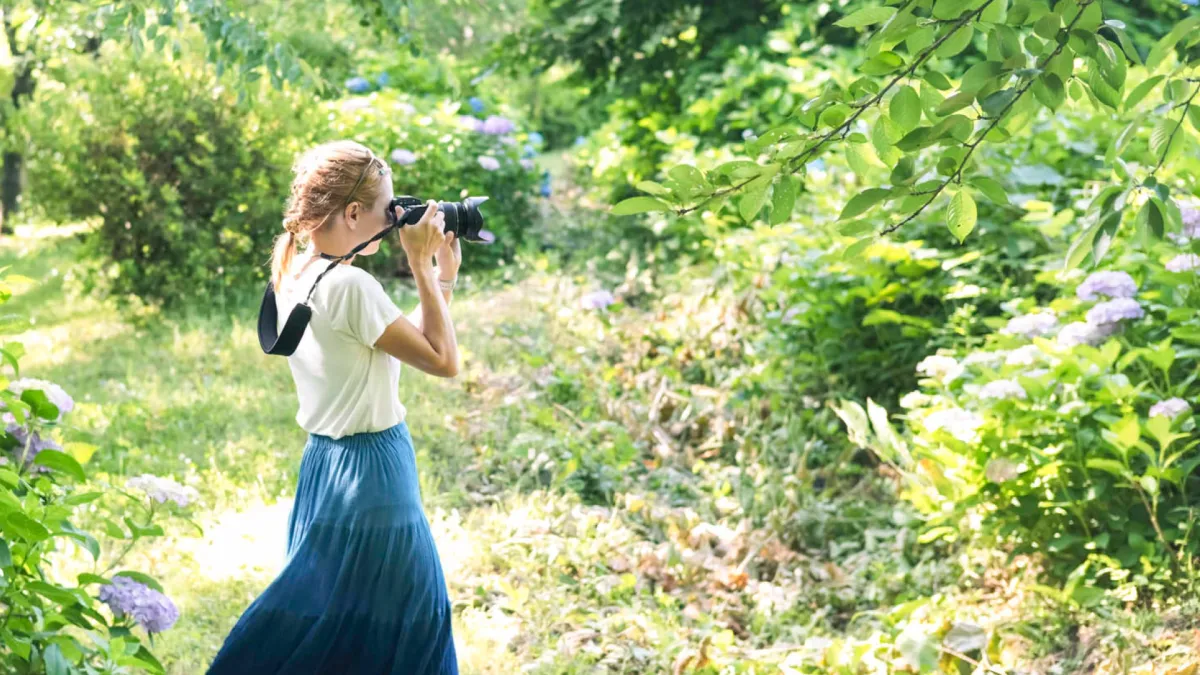 A girl takes a pic with her camera in the woods