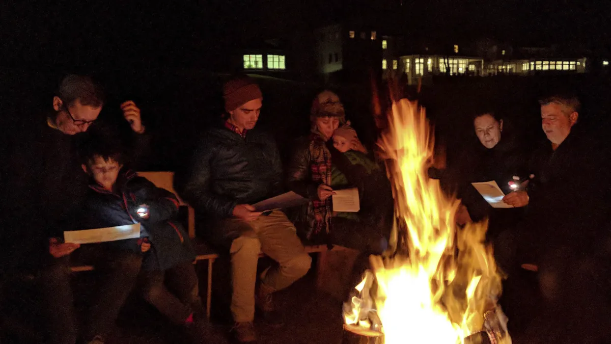 A group of families gather at the bonfire. 