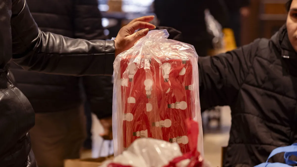A lady picks up a wrapped gift in line. 