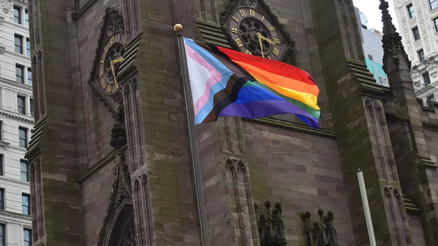 The Progress Pride Flag flies in front of Trinity Church Wall Street