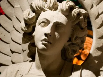 Stone angel statue and stained glass in background