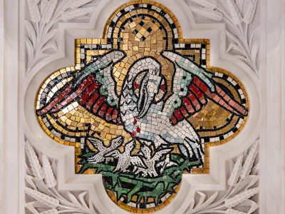 Tile mosaic image of a crane feeding its chicks on a gold background