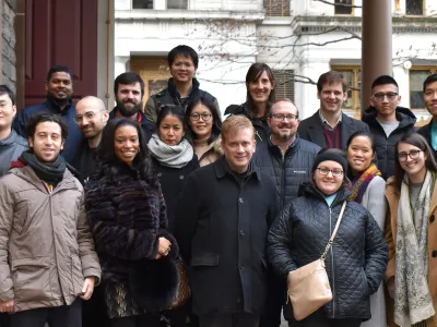 A group of young adults smiles on the steps of St. Paul's Chapel