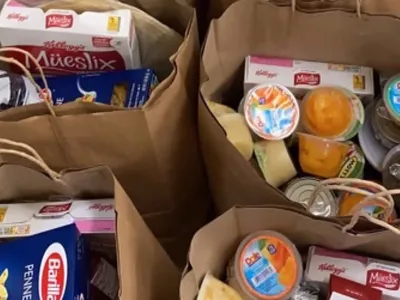 Brown bags of groceries full of shelf-stable healthy food such as pasta and canned goods.