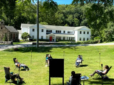 Socially-distanced group meets in a circle on the shaded green lawn of the Retreat Center