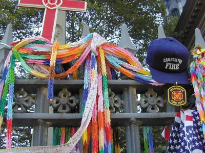 Flags, garlands, hats, a cross, and other memorial items hung on the fence surrounding St. Paul's Chapel