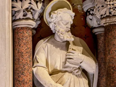 Statue in Trinity Church in marble and plaster, a saint holding a book.