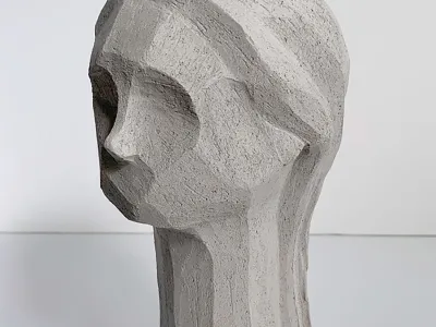 A gray slay sculpture of an abstract human bust