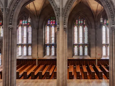 A wide shot of empty pews against a wall of stained glass windows in Trinity Church Wall Street