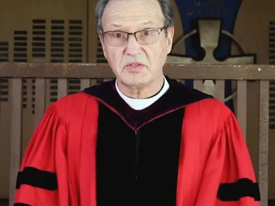 CDSP's Mark Richardson in red vestments speaking at Commencement.