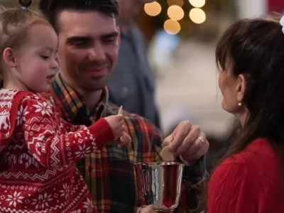 chalice bearer offers chalice to man and child during communion