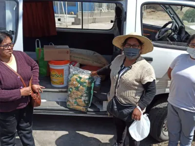 Women stand in front of a van with doors open showing food items