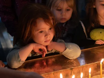 Children look peer onto a table of lit candles in St. Paul's Chapel