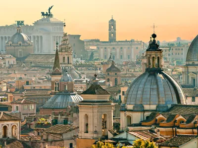 Spires and bell towers make up the skyline of Rome against a sunset