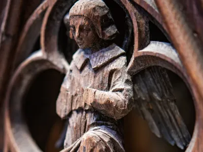 A person kneeling in prayer, depicted on a wood carving in Trinity Church