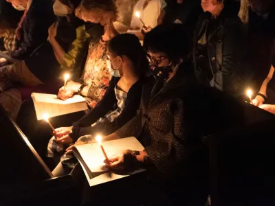 Parishioners holding candles in a dark Trinity Church