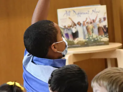 A child raises their hand during Children's Time at Trinity Commons