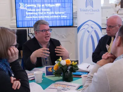 Four Trinity Institute participants sit around a table, discussing a topic and listening to one another.