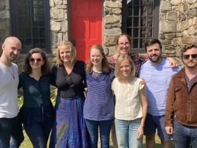 A group of young adults gathers in front of the stone chapel at Trinity Retreat Center