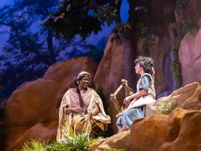 A production photo from DAVID showing a shepherd boy and a woman on a rocky set