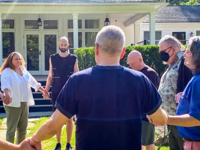 Retreatants hold hands in prayer and sunshine