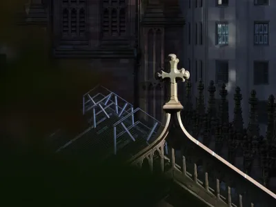 Afternoon light spotlights a cross on the top of Trinity Church Wall Street in Lower Manhattan