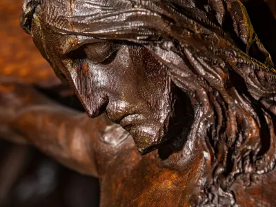 A close-up photo of a wood carving of Jesus on the cross