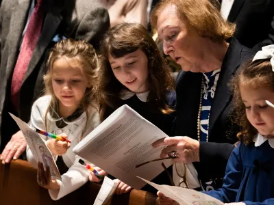 Children and an adult read through the worship bulletin together during worship at Trinity Church