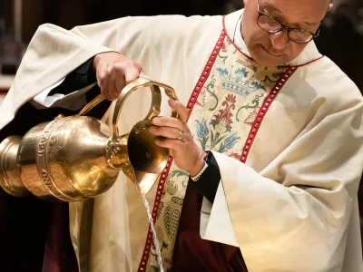 Father Phil pours water into the baptismal font in Trinity Church