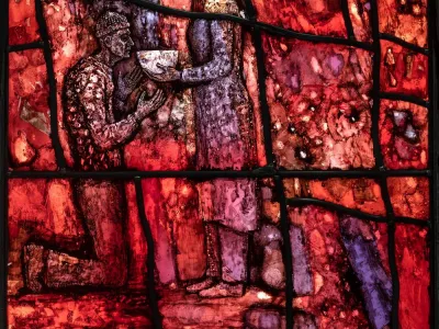 Stained-glass window closeup of woman feeding a person in need.