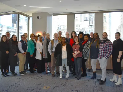 Group of people smile at camera while standing in a conference room.