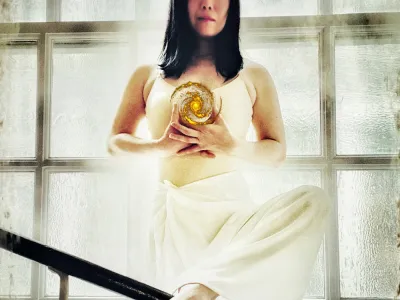 A dancer stands in front of a light-filled window in St. Paul's Chapel with a small universe floating in their hands