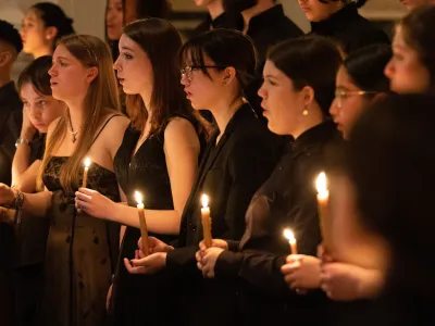Teenagers in black clothes singing while holding candles