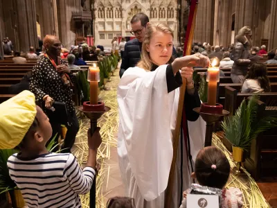 Emily Smith lighting candles with two young parishioners on Palm Sunday, 2023